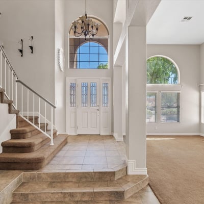 From the grand front entrance, enjoy views into the expansive living space featuring soaring ceilings, oversized windows, and abundant natural light. The open design enhances both comfort and entertaining.