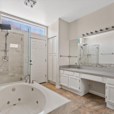 The primary bathroom offers an oversized vanity, glass walk-in shower, jetted soaking tub, and plentiful storage. Modern finishes and spacious design create a true spa-inspired retreat.
