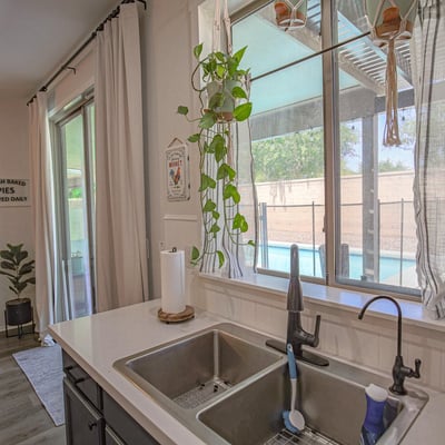 Functional kitchen workspace with a modern sink, quartz countertops, updated fixtures, and relaxing views of the covered patio and sparkling backyard pool, blending style with everyday convenience.
