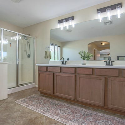 Elegant primary bathroom with an extended dual-sink vanity, oversized mirror, updated lighting, soaking tub, and separate glass shower. A spacious and functional owner's retreat.