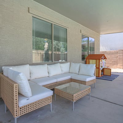 Relaxing covered patio featuring comfortable outdoor seating and views of the backyard entertaining space. A welcoming extension of the home's living area in this desirable Waddell property.