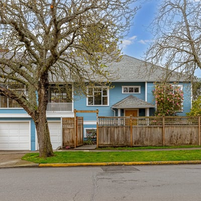 Spacious blue home with a fenced yard, featuring unique architecture and convenient garage access.