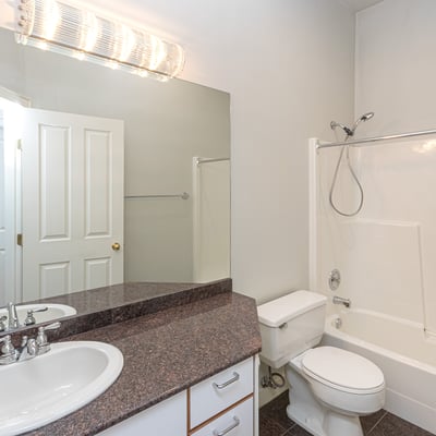 Well-appointed bathroom featuring dual sinks, modern fixtures, and a convenient tub-shower combination.
