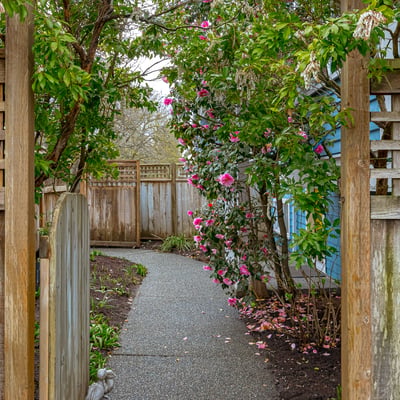Discover a welcoming pathway adorned with vibrant blooms, leading to a private outdoor retreat.