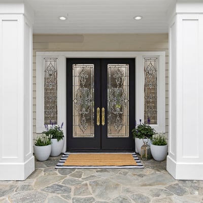 Inviting entrance featuring decorative beveled glass doors, vibrant planters, and a tasteful stone pathway, perfect for welcoming guests.