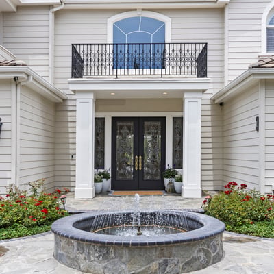 Elegant private entryway features a tranquil fountain and landscaped gardens, creating an inviting first impression.
