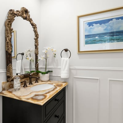 Downstairs Guest Bath-This inviting bathroom features a unique stone vanity , custom wainscoting and coastal-themed artwork, enhancing its modern appeal.