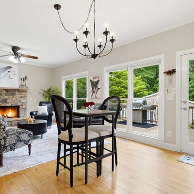 Spacious living area features a cozy fireplace and direct access to a private deck surrounded by greenery.