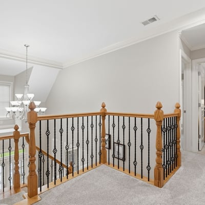 This spacious second-floor landing features a modern chandelier and leads to cozy, well-lit bedrooms.