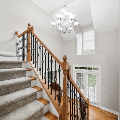 Bright and inviting entryway features a spacious staircase with elegant railings and abundant natural light.