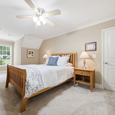 Bright and inviting bedroom featuring plush carpeting, modern ceiling fan, and ample natural light.