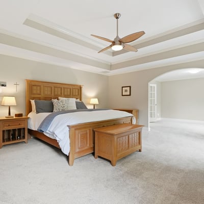 Spacious master bedroom with tray ceiling, abundant natural light, and an adjoining versatile living area.