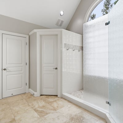 Modern bathroom featuring a spacious walk-in shower with frosted glass and natural light.