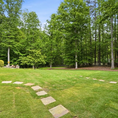 Expansive backyard featuring a winding stone pathway, surrounded by mature trees for added privacy and greenery.
