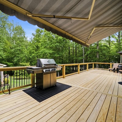 Expansive deck with built-in grill, surrounded by lush greenery, perfect for outdoor gatherings and relaxation.