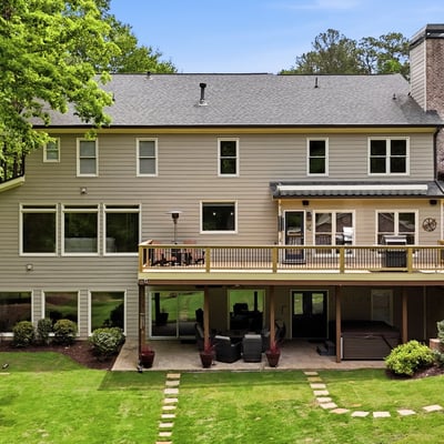Spacious home with expansive outdoor deck, large windows, and a beautifully landscaped backyard ideal for gatherings.