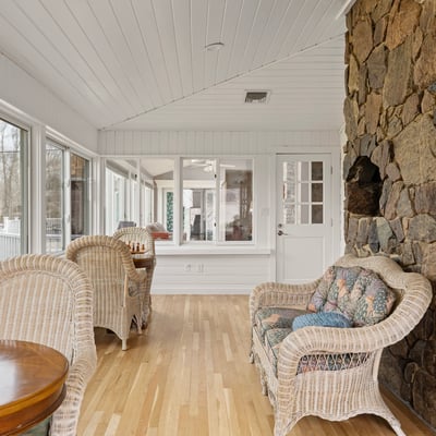 Light-filled sunroom featuring a stone wall, perfect for relaxation or entertaining with expansive views.