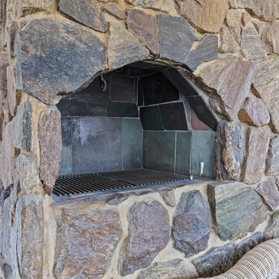 Discover a unique outdoor space featuring a robust stone fireplace, perfect for gatherings and cooking.