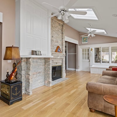 Bright and airy living space featuring a stone fireplace and large windows, perfect for entertaining or relaxing.