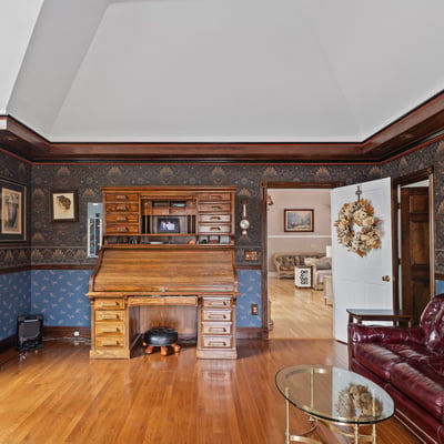 Spacious living area featuring distinctive woodwork, a classic desk, and inviting natural light throughout.
