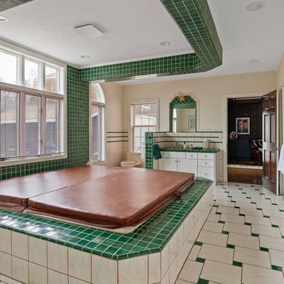 Spacious bathroom featuring a large sunken tub, extensive green tilework, and ample natural light.