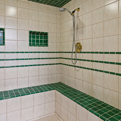 Spacious walk-in shower featuring unique green tile accents and built-in seating for added convenience.