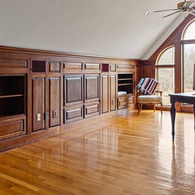 Bright, spacious office featuring wooden paneling, ample storage, and large windows for natural light.