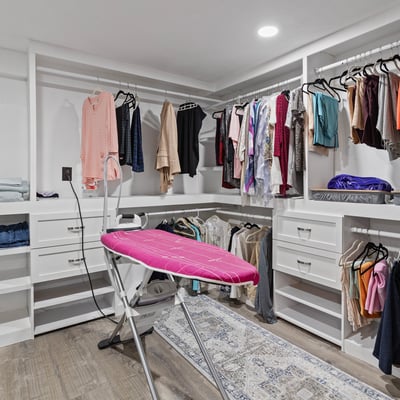 Spacious walk-in closet equipped with ample storage and a convenient ironing station for modern living.