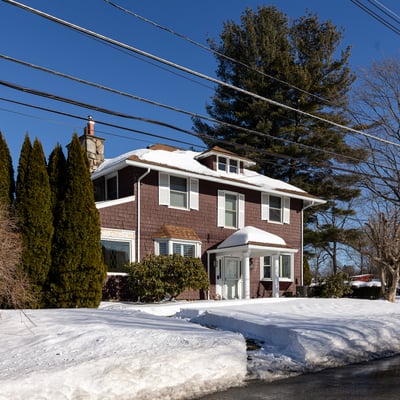 Spacious two-story home surrounded by trees, featuring ample outdoor space and winter scenery.