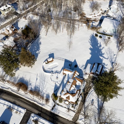 Stunning aerial view of a winter landscape featuring a spacious property amidst a pristine snowy backdrop.