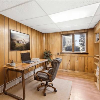 Bright and inviting home office featuring warm wooden walls and ample natural light for productivity.