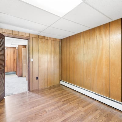 Spacious room featuring wood paneling, natural light, and convenient access to additional living areas.