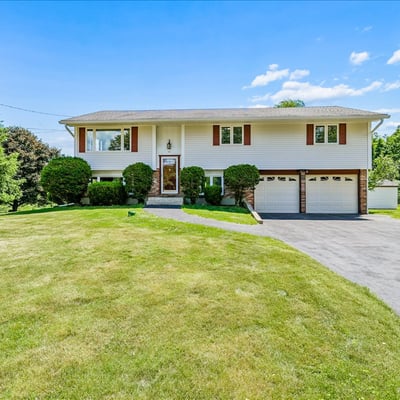 Spacious split-level home with ample yard space, featuring a welcoming entrance and dual garages.