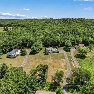 Spacious property surrounded by lush woodland, featuring multiple homes and expansive open space for various uses.