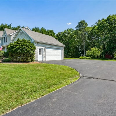 This spacious home features a circular driveway and lush landscaping, perfect for outdoor gatherings and privacy.