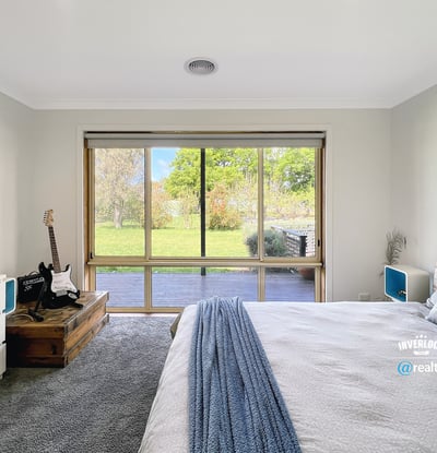 Bright bedroom featuring a large window with garden views, complemented by modern furnishings and cozy atmosphere.