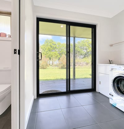 Bright laundry room featuring a washing machine, ample storage, and direct access to the outdoor space.