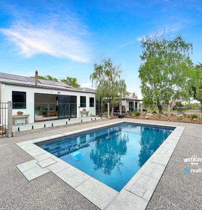 This contemporary home features a spacious outdoor area with a pristine pool and landscaped surroundings.