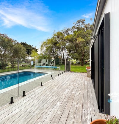 Discover a modern retreat featuring a spacious deck and inviting pool surrounded by lush greenery.