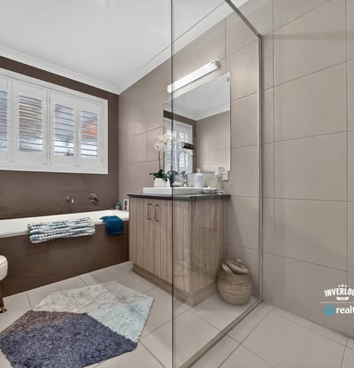 Modern bathroom featuring a spacious walk-in shower, double vanity, and natural light from large windows.