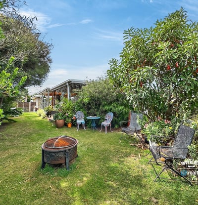 Nestled in lush greenery, this inviting outdoor space features seating areas and a fire pit for gatherings.