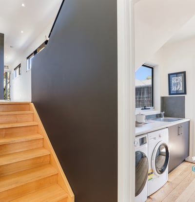 Modern entryway features a bright, airy stairway alongside a convenient laundry area and outdoor access.