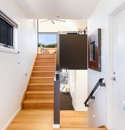 Bright entryway with modern design, featuring warm wood accents and an inviting staircase leading to open spaces.