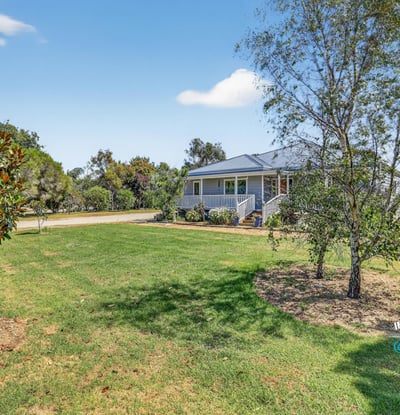 Discover this inviting home surrounded by lush greenery and ample outdoor space for relaxation and activities.