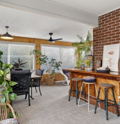 Bright sunroom featuring a cozy bar, abundant greenery, and ample natural light for relaxation and entertainment.