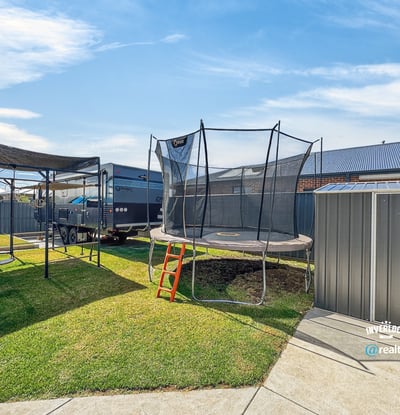 Spacious backyard featuring a trampoline, perfect for outdoor fun and family gatherings, with ample storage options.