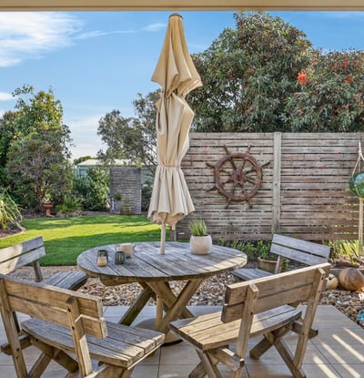 Enjoy outdoor living in this inviting patio, featuring a cozy seating area and lush greenery.