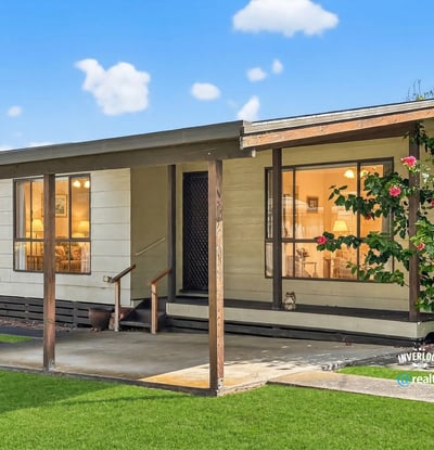 This inviting home features a spacious front porch and lush landscaping, perfect for outdoor relaxation.