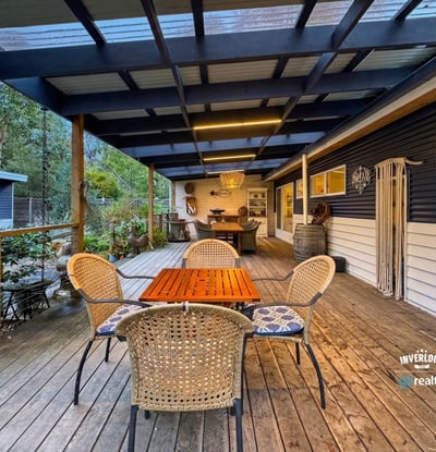 Spacious outdoor deck ideal for entertaining, featuring a cozy dining area and surrounding natural greenery.