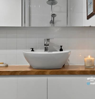 Modern bathroom featuring a sleek vessel sink on a wooden countertop, complemented by tasteful decor.